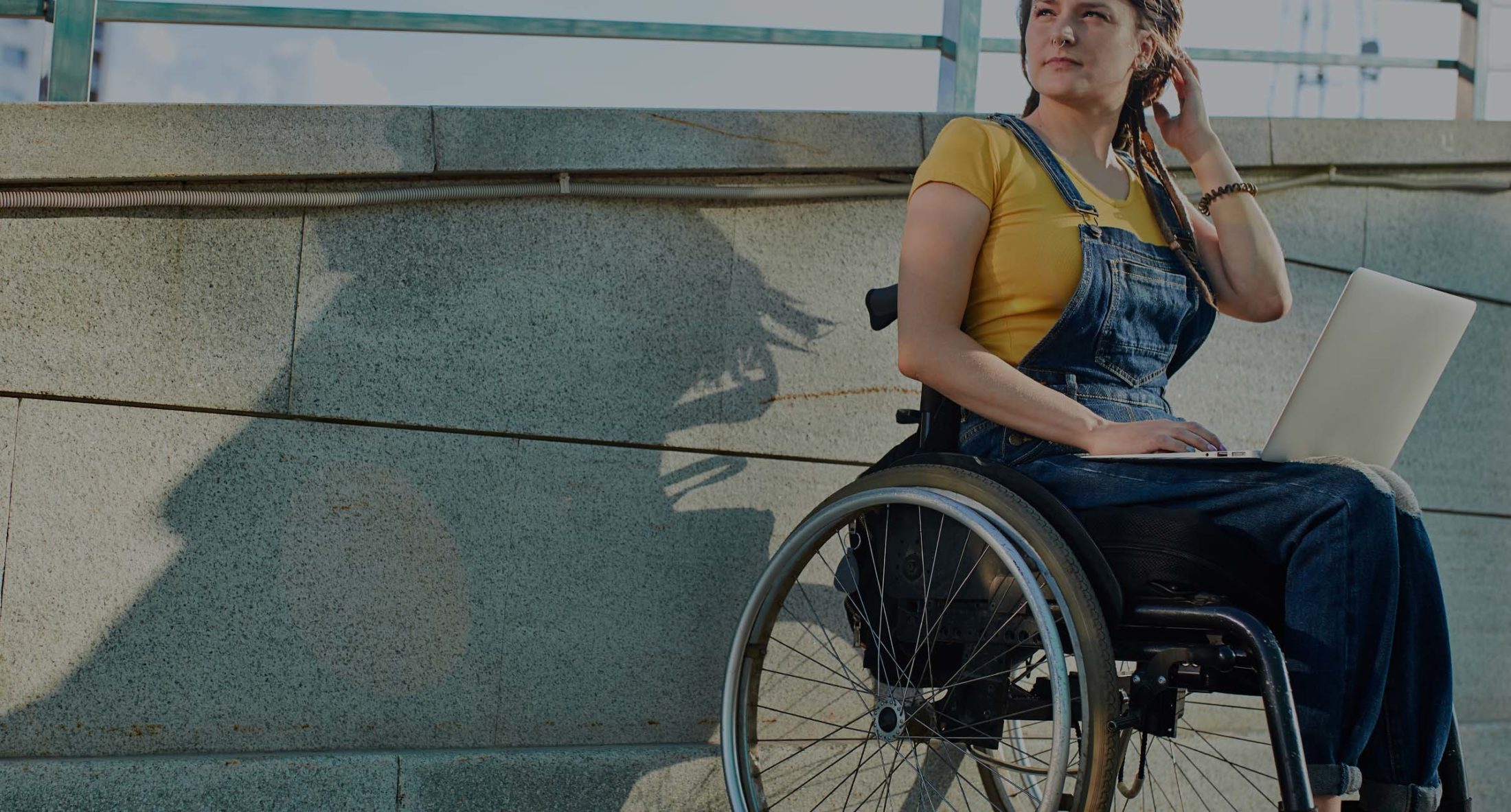 Woman who has experienced spinal cord injury sits outside in wheelchair with laptop